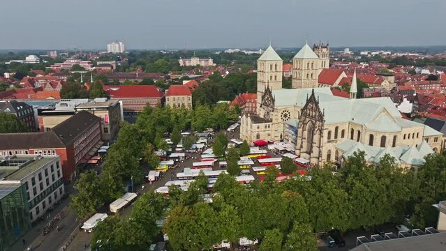An aerial drone shot of St. Paulus Dom, also known as M&uuml;nster Cathedral, on Domplatz in M&uuml;nster on a sunny day. It is a central and culturally significant area of central M&uuml;nster, Germany. Busy Market