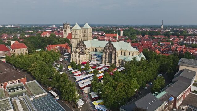 An aerial drone shot of St. Paulus Dom, also known as M&uuml;nster Cathedral, on Domplatz in M&uuml;nster on a sunny day. It is a central and culturally significant area of central M&uuml;nster, Germany. Busy Market
