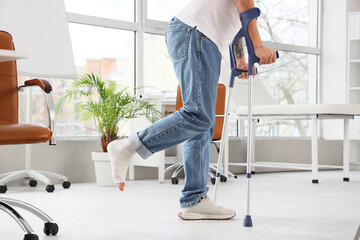 Injured young man after accident with crutches walking in clinic