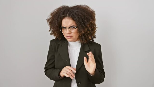 Disgusted hispanic woman with curly hair fearfully exposes aversion with raised hands and negative expression, isolated on white background