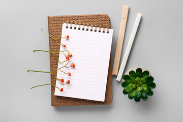 Notebook, stationery and dried flowers on grey background