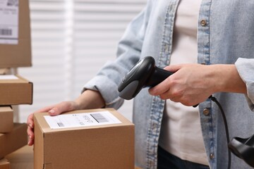 Parcel packing. Post office worker with scanner reading barcode indoors, closeup