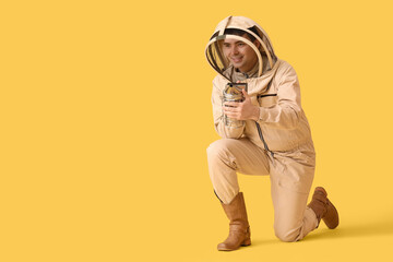 Male beekeeper with smoker on yellow background