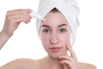 Young woman with acne problem applying cosmetic product onto her skin on white background