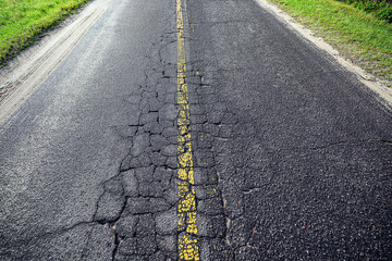 damaged cracked asphalt road faded yellow strip