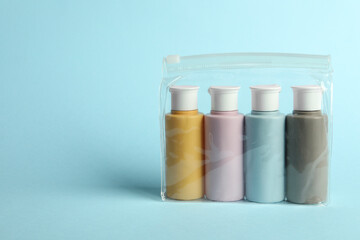 Cosmetic travel kit in plastic bag on light blue background. Space for text