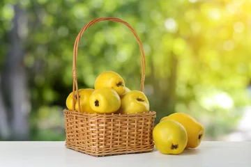 Schilderijen op glas Basket with delicious fresh ripe quinces on white wooden table outdoors © New Africa