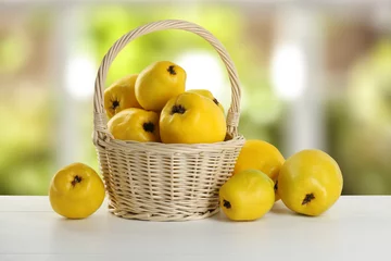 Schilderijen op glas Basket with delicious fresh ripe quinces on white wooden table outdoors © New Africa