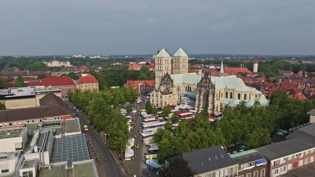 An aerial drone shot of St. Paulus Dom, also known as M&uuml;nster Cathedral, on Domplatz in M&uuml;nster on a sunny day. It is a central and culturally significant area of central M&uuml;nster, Germany. Busy Market