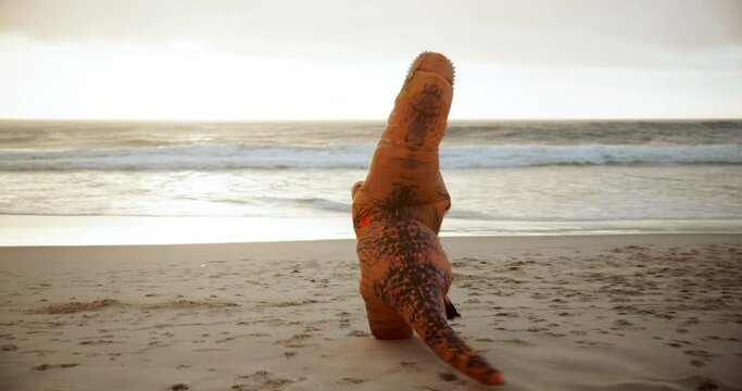 Beach, inflatable and dinosaur costume and comic, sunset and ocean at sunrise. Summer, funny and running in nature for weird prehistoric doll, crazy and prank for celebration or initiation into club