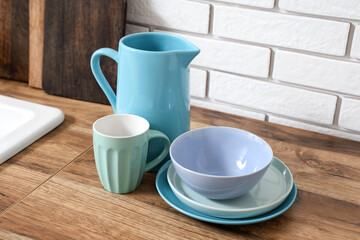 Stack of blue clean tableware on wooden table near white brick wall