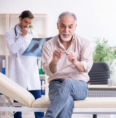 Young male doctor and old patient in antismoking concept - 782614249