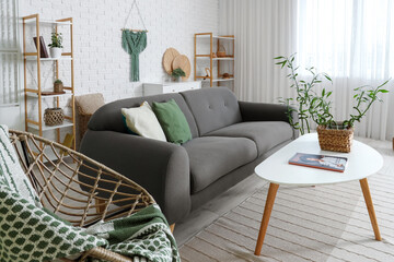 Light interior of modern living room with bamboo stems on coffee table, armchair and sofa