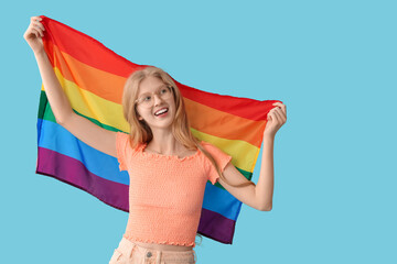Beautiful young happy woman with LGBT flag on blue background