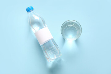 Plastic bottle of clean water and glass on blue background