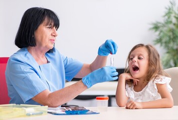 Little girl visiting old female doctor - 782624059