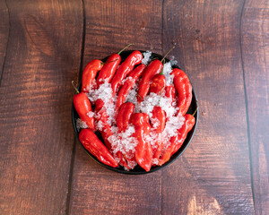 Hot peppers on ice, on a black plate. Zenithal shot.