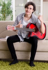 Young man with guitar at home - 782625865