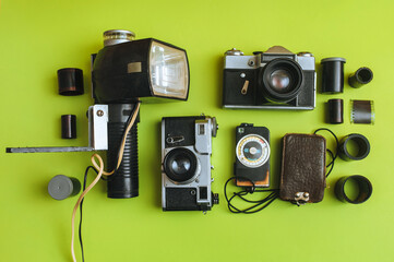 A set of rare photographic equipment. Camera, flash, film and exposure meter on a green background....
