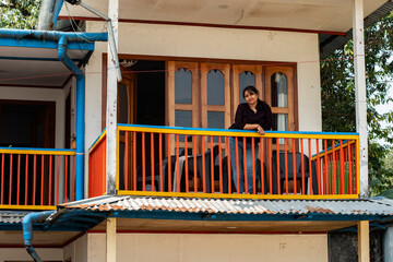 An young beautiful traveler standing at balcony area of a resort enjoying nature.