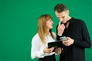 man and woman with gadgets tablet phone in hands on green background talking laugh holding meeting learning to work on Internet flirting relationships flirting couple solving issue positive emotions