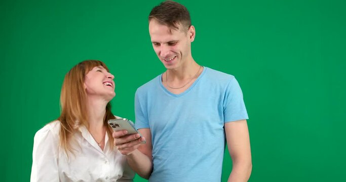 Picture of a young couple watching a funny video on mobile phone, posing on isolated background