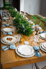 Table setting at wedding private event, white plates, life greenery centerpieces