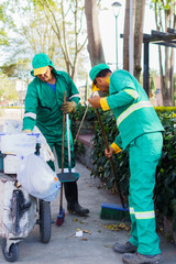 two street sweepers collecting garbage and dry leaves from a park in the day