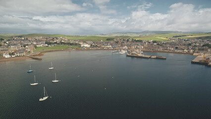 Yachts regatta at pier town cityscape aerial. Buildings at traffic road with cars. Wharf with water transport at ocean bay. Scotland Campbeltown city attraction at summer cruise on sailboats race