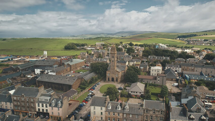 Fototapeta na wymiar Europe cityscape at traffic road with cars, trucks aerial. Historic buildings at urban streets of Campbeltown city, Scotland. Downtown houses and architecture landmark. Cinematic drone shot