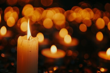 Lit candle on a dark background with bokeh