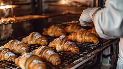 Keuken spatwand met foto A baker pulling freshly baked croissants out of the oven © KerXing