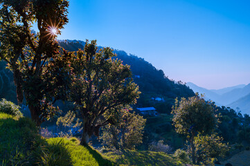 Landscape with sky. Serene peaceful view of Himalayan mountains in the  Kumaun region village. Showing hues at dusk sunrise with sun rays passing between mountains. Uttarakhand, India.