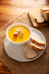 Homemade carrot and pumpkin cream soup. Easy, nutritious and healthy recipe. Served in a white bowl with bread croutons. Perfect to accompany everyday food.