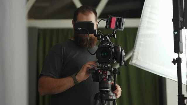 Professional cameraman preparing equipment before shooting a movie. Smiling funny guy camera operator ready to shoot. Video production specialist. Stock videos cameraman concentrated on his job in