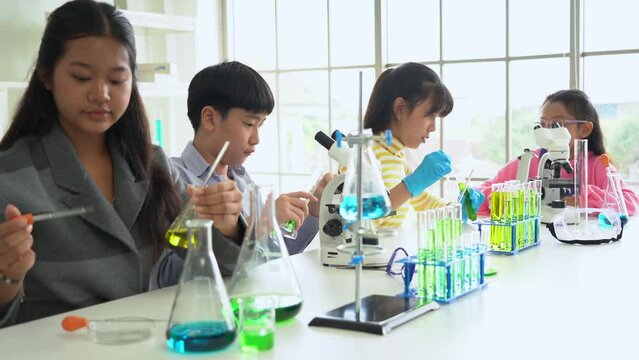 Group Of Excited Asian School Kid Doing Chemical Experiment In Laboratory Together. Pupil Students Science Testing Chemistry Class In The Lab Together