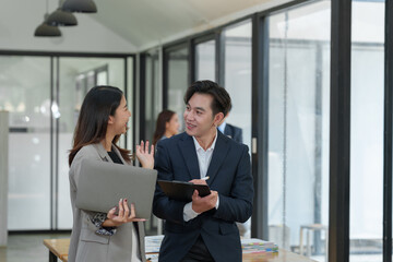 The creative team, a man, and two Asian women smile and talk. Discuss numbers financial information and calculations. online marketing Tracking the company's operating results and profits.