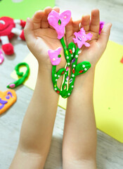 Child making bouquet, flowers from plasticine, clay, beads. little girl creating gift for mom gift for Mothers day, Birthday or Valentines day . Arts  crafts concept.