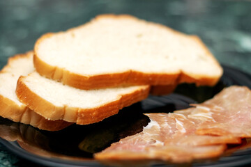 Food ingredients like slices of meat and bread served on black plate