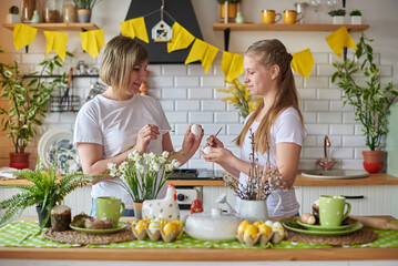 Mom and daughter in the kitchen prepare for Easter and paint eggs