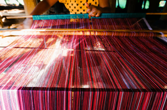 a girl making traditional woven fabric