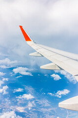 Fototapeta premium View from the airplane window at a beautiful cloudy sky and the airplane wing