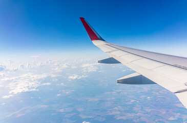 Obraz premium View from the airplane window at a beautiful cloudy sky and the airplane wing