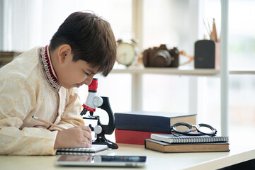 Indian child boy wearing traditional clothes and using microscope, learning about microbes