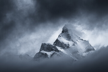 Moody black and white landscape view of a mountain appearing in the dark clouds