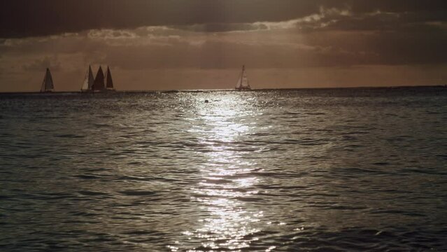 View of the sea at sunset on Waikiki Beach, with boats sailing in the distant background in Hawaii