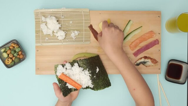 Top shot of two Hands preparing Sushi on blue table