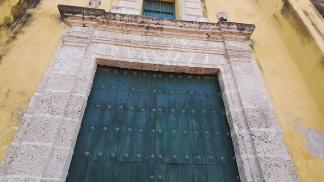 Massive green door and golden-painted facade of Holy Trinity church, Cartagena