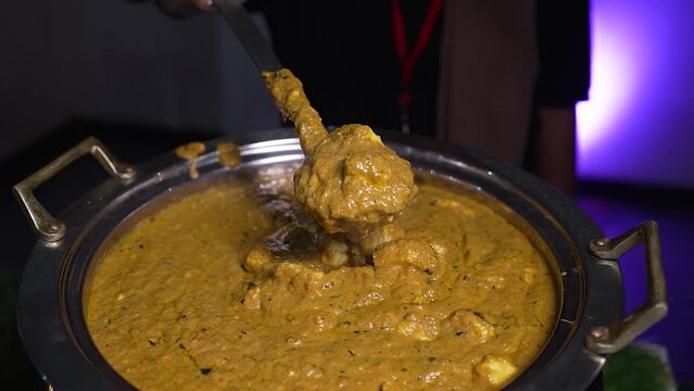 Close-up of paneer butter masala in an Indian buffet restaurant. The server showing the freshly prepared curry in a Chafing Dish.