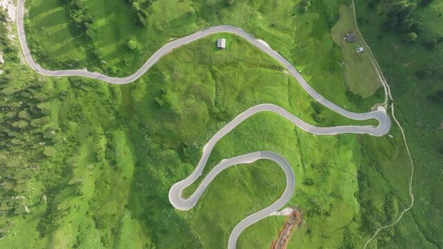 Aerial view of a single car driving on the winding road of Passo Gardena in the Dolomites Mountains, Trentino, South Tyrol, Italy. LuPa Creative.